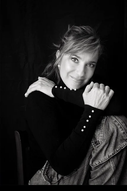 Black-and-white portrait of Mariana Yáñez resting her chin on her folded arms against a dark backdrop.