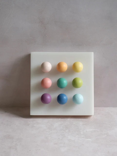 Confetti by Paola del Valle — a white square panel set with a three-by-three grid of nine matte pastel orbs in blush, orange, yellow, teal, lime, purple, and blue.